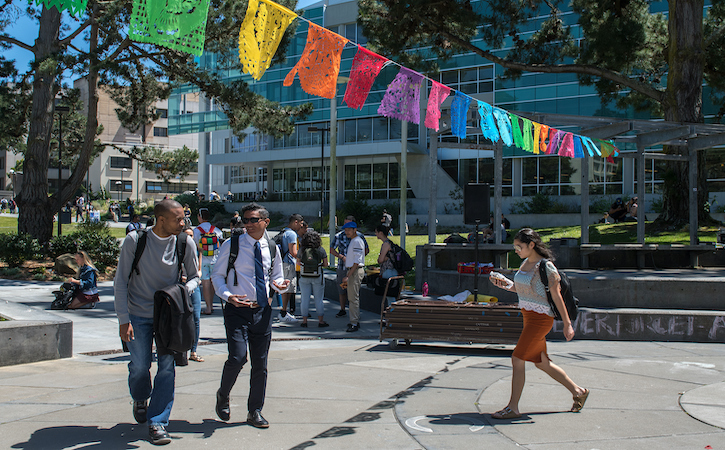 Students walking on campus with colorful flags above them