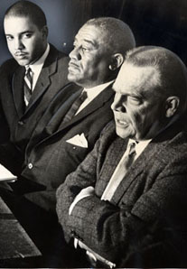 Three men in suits sitting with arms folded